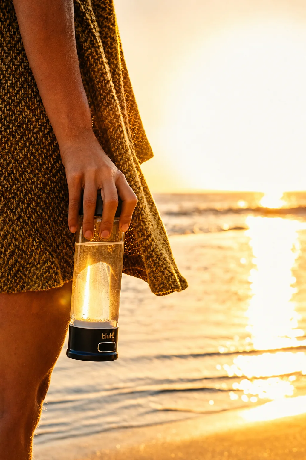 Person holding a BluH2 bottle beside the ocean