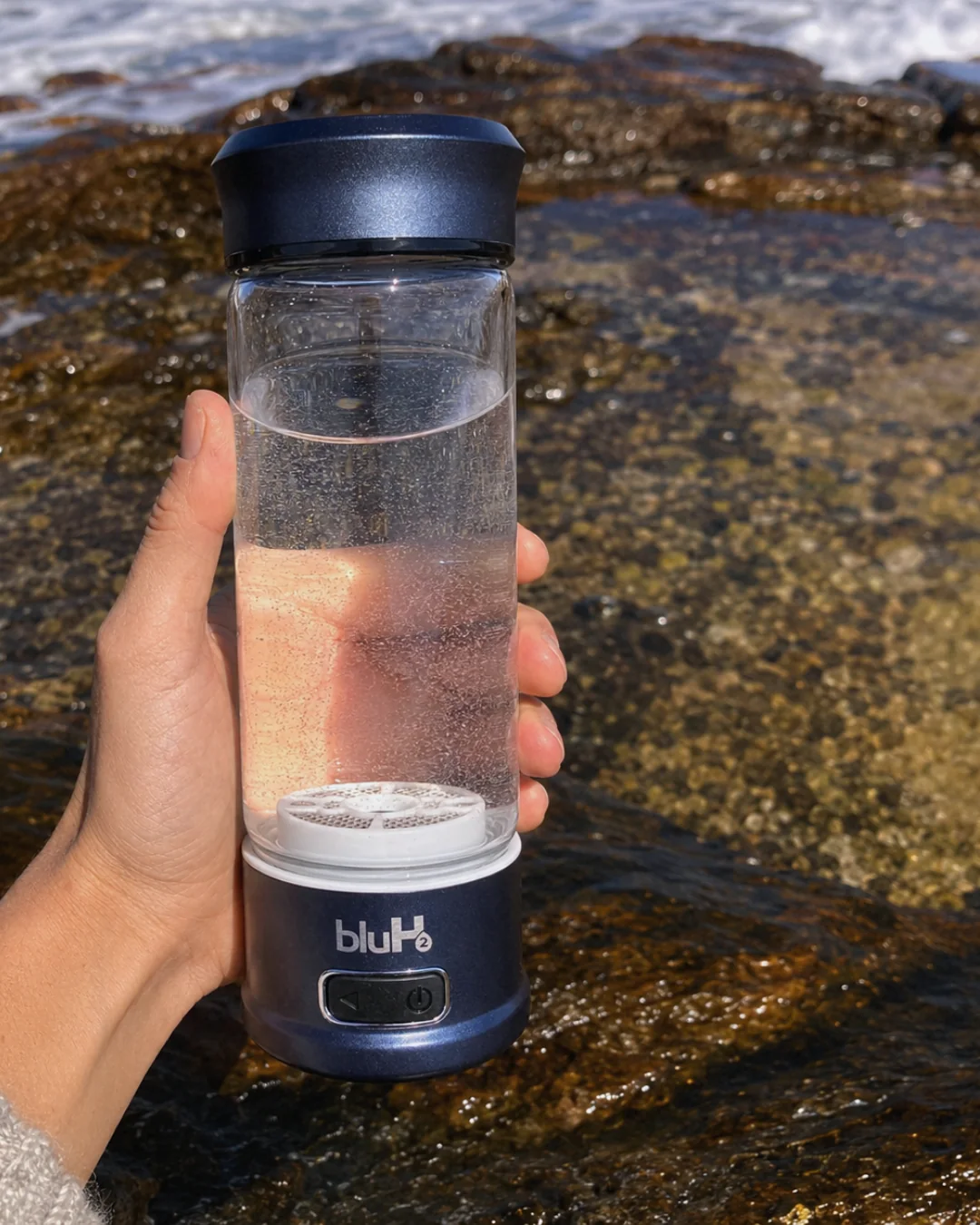 Close-up of a BluH2 Flow bottle held beside the water